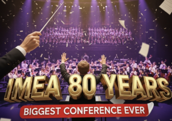 A viral, hyper-realistic YouTube thumbnail with a cinematic concert hall atmosphere. The background is the packed Grand Wayne Convention Center stage filled with hundreds of young musicians performing under dramatic purple and gold spotlights with subtle confetti falling. The composition uses a dramatic low-angle shot to focus on the main subject: a gleaming conductor's baton raised triumphantly in the foreground with sheet music pages flying around it. The image features massive 3D typography with strict hierarchy: The Primary Text reads exactly: 'IMEA 80 YEARS'. This text is massive, the largest element in the frame, rendered in polished gold chrome with glowing edges to look like a high-budget 3D render. The Secondary Text reads exactly: 'BIGGEST CONFERENCE EVER'. This text is significantly smaller, positioned below the main text with a bold red sticker-style outline and slight shadow effect. The text materials correspond to the story's concept. Crucial Instruction: There is absolutely NO other text, numbers, watermarks, or subtitles in this image other than these two specific lines. 8k, Unreal Engine 5, cinematic render