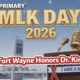 A viral, hyper-realistic YouTube thumbnail with a powerful, hopeful civil rights atmosphere. The background is a crisp winter morning over downtown Fort Wayne with the Martin Luther King Jr. Bridge prominently visible and gentle snow falling. The composition uses a dramatic low-angle shot to focus on the main subject: a large, polished bronze microphone standing on a wooden podium with an "I Have a Dream" ribbon banner draped across it. The image features massive 3D typography with strict hierarchy: The Primary Text reads exactly: 'MLK DAY 2026'. This text is massive, the largest element in the frame, rendered in gleaming gold chrome with subtle glowing edges to look like a high-budget 3D render. The Secondary Text reads exactly: 'Fort Wayne Honors Dr. King'. This text is significantly smaller, positioned below the main text with a thick white outline and red sticker-style border to pop against the cool blue sky. The text materials correspond to the story's concept. Crucial Instruction: There is absolutely NO other text, numbers, watermarks, or subtitles in this image other than these two specific lines. 8k, Unreal Engine 5, cinematic render