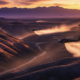 A viral, hyper-realistic YouTube thumbnail with a dramatic western wildfire recovery atmosphere. The background is a vast blackened Colorado landscape at golden hour with massive helicopters kicking up dust while dropping seed over steep burn scars, distant purple mountains under a fiery sunset sky. The composition uses a low-angle cinematic shot to focus on the main subject: a huge spinning helicopter rotor blade in sharp detail. The image features massive 3D typography with strict hierarchy: The Primary Text reads exactly: 'COLORADO FIGHTS BACK'. This text is massive, the largest element in the frame, rendered in molten orange chrome with glowing embers flying off the letters like real fire particles. The Secondary Text reads exactly: '265,000 Acres Rising'. This text is significantly smaller, positioned below the main text with a thick white outline and red glow border to pop against the dark terrain. 8k, Unreal Engine 5, cinematic render.