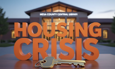 A viral, hyper-realistic YouTube thumbnail with a Business/Community atmosphere. The background is a blurred, high-quality shot of the Mesa County Central Library exterior at twilight with warm, inviting lighting. The composition uses a slightly Low Angle to focus on the main subject: a detailed 3D House Key resting on a wooden table. The image features massive 3D typography with strict hierarchy: The Primary Text reads exactly: 'HOUSING CRISIS'. This text is massive, the largest element in the frame, rendered in Matte Orange to look like a high-budget 3D render. The Secondary Text reads exactly: 'SPEAK UP TONIGHT'. This text is significantly smaller, positioned below the main text. It features a thick, distinct white border/outline (sticker style) to contrast against the background. Make sure text 2 is always different theme, style, effect and border compared to text 1.