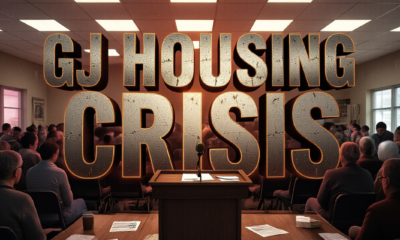 A viral, hyper-realistic YouTube thumbnail with a tense, urgent western Colorado atmosphere. The background is a crowded community center room packed with worried residents under harsh fluorescent lights mixed with dramatic red emergency-style glow. The composition uses a low, slightly tilted angle to focus on the main subject: a cracked wooden podium with a microphone and scattered housing survey forms. The image features massive 3D typography with strict hierarchy: The Primary Text reads exactly: 'GJ HOUSING CRISIS'. This text is massive, the largest element in the frame, rendered in weathered brushed steel with glowing orange edges to look like a high-budget 3D render. The Secondary Text reads exactly: 'RESIDENTS DEMAND ACTION'. This text is significantly smaller, positioned below the main text. It features a thick, distressed white outline with red drop shadow to contrast against the background. Make sure text 2 is always different theme, style, effect and border compared to text 1. The text materials correspond to the story's concept. Crucial Instruction: There is absolutely NO other text, numbers, watermarks, or subtitles in this image other than these two specific lines. 8k, Unreal Engine 5, cinematic render