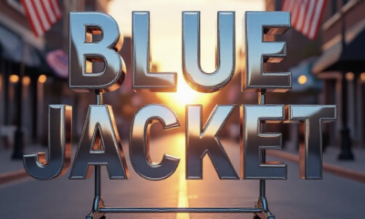 A viral, hyper-realistic YouTube thumbnail with a hopeful, warm community atmosphere. The background is a softly lit Fort Wayne street at golden hour with American flags waving gently. The composition uses a low-angle cinematic shot to focus on the main subject: a gleaming empty metal clothing rack dramatically spotlighted in the center. The image features massive 3D typography with strict hierarchy: The Primary Text reads exactly: 'BLUE JACKET'. This text is massive, the largest element in the frame, rendered in polished chrome with subtle blue glow to look like a high-budget 3D render. The Secondary Text reads exactly: 'NEEDS YOUR SUITS NOW'. This text is significantly smaller, positioned below the main text. It features a thick, urgent red border/outline (sticker style) to contrast against the background. Make sure text 2 is always different theme, style, effect and border compared to text 1. The text materials correspond to the story's concept. Crucial Instruction: There is absolutely NO other text, numbers, watermarks, or subtitles in this image other than these two specific lines. 8k, Unreal Engine 5, cinematic render