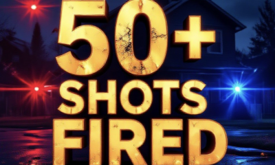 A viral, hyper-realistic YouTube thumbnail with a tense crime-night atmosphere. The background is a dark suburban street in Grand Junction, Colorado at night with red and blue police lights flashing across quiet homes and scattered shell casings glowing on wet pavement. The composition uses a dramatic low-angle shot to focus on the main subject: a bullet-riddled house exterior with a clear bullet hole in the siding. The image features massive 3D typography with strict hierarchy: The Primary Text reads exactly: '50+ SHOTS FIRED'. This text is massive, the largest element in the frame, rendered in glowing hot orange metal with bullet impact sparks flying off the letters. The Secondary Text reads exactly: 'Grand Junction Still Searching'. This text is significantly smaller, positioned below the main text with a thick white outline and red sticker-style border to pop against the dark background. There is absolutely NO other text, numbers, watermarks, or subtitles in this image other than these two specific lines. 8k, Unreal Engine 5, cinematic render