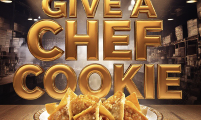 A viral, hyper-realistic YouTube thumbnail with a warm, bustling kitchen atmosphere. The background is a packed Grand Junction warehouse venue with dramatic overhead spotlights cutting through steam. The composition uses a low-angle shot to focus on the main subject: a gleaming trophy plate holding chicken-peanut curry wonton tacos with crushed Peanut Butter Patties visibly embedded in golden shells. The image features massive 3D typography with strict hierarchy: The Primary Text reads exactly: 'GIVE A CHEF A COOKIE'. This text is massive, the largest element in the frame, rendered in molten caramel gold chrome to look like a high-budget 3D render. The Secondary Text reads exactly: 'SAVORY COOKIE WINNERS 2026'. This text is significantly smaller, positioned below the main text. It features a thick, electric lime-green border/outline (sticker style) to contrast against the background. Make sure text 2 is always different theme, style, effect and border compared to text 1. The text materials correspond to the story's concept. Crucial Instruction: There is absolutely NO other text, numbers, watermarks, or subtitles in this image other than these two specific lines. 8k, Unreal Engine 5, cinematic render