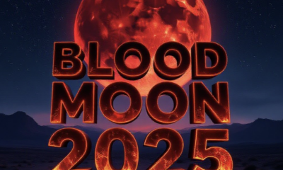 A viral, hyper-realistic YouTube thumbnail with a dramatic cosmic atmosphere. The background is a vast starry night sky over a dark desert landscape with distant mountains, illuminated by intense crimson moonlight. The composition uses a low-angle shot looking up to focus on the main subject: a massive, perfectly round blood-red moon dominating the sky. The image features massive 3D typography with strict hierarchy: The Primary Text reads exactly: 'BLOOD MOON 2025'. This text is massive, the largest element in the frame, rendered in glowing molten lava material with realistic 3D depth and ember particles to look like a high-budget cinematic render. The Secondary Text reads exactly: 'LONGEST ECLIPSE OF THE DECADE'. This text is significantly smaller, positioned below the main text with a thick neon-blue electric outline and subtle lightning crackle effect to contrast against the red background. Make sure text 2 is always different theme, style, effect and border compared to text 1. The text materials correspond to the story's concept. Crucial Instruction: There is absolutely NO other text, numbers, watermarks, or subtitles in this image other than these two specific lines. 8k, Unreal Engine 5, cinematic render