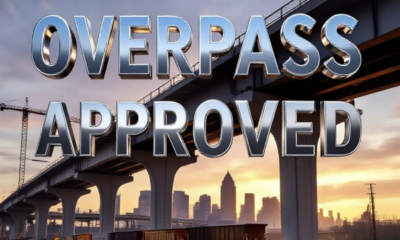 A viral, hyper-realistic YouTube thumbnail with a dramatic urban infrastructure atmosphere. The background is a massive construction site at golden hour with Fort Wayne skyline faint in distance, heavy machinery and steel beams rising. The composition uses a low dramatic camera angle to focus on the main subject: a gleaming new concrete overpass structure soaring upward with a freight train passing underneath. Image size should be 3:2. The image features massive 3D typography with strict hierarchy: The Primary Text reads exactly: 'OVERPASS APPROVED'. This text is massive, the largest element in the frame, rendered in polished chrome metal with glowing orange edges to look like a high-budget 3D render. The Secondary Text reads exactly: 'Ends Train Delays Forever'. This text is significantly smaller, positioned below the main text. It features a thick white border with red glow outline (sticker style) to contrast against the background. Make sure text 2 is always different theme, style, effect and border compared to text 1. The text materials correspond to the story's concept. Crucial Instruction: There is absolutely NO other text, numbers, watermarks, or subtitles in this image other than these two specific lines. 8k, Unreal Engine 5, cinematic render.