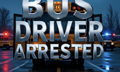 A viral, hyper-realistic YouTube thumbnail with a dark, tense crime atmosphere. The background is a rainy Colorado school bus parking lot at dawn with police lights flashing red and blue across wet pavement. The composition uses a low-angle shot to focus on the main subject: a yellow school bus with open doors and police tape across it. Image size should be 3:2. The image features massive 3D typography with strict hierarchy: The Primary Text reads exactly: 'BUS DRIVER ARRESTED'. This text is massive, the largest element in the frame, rendered in cold chrome metal with dripping wet effects to look like a high-budget 3D render. The Secondary Text reads exactly: 'Child Sex Assault'. This text is significantly smaller, positioned below the main text. It features a thick, blood-red border/outline (sticker style) to contrast against the dark background. Make sure text 2 is always different theme, style, effect and border compared to text 1.