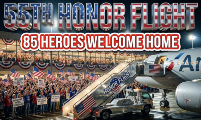 A viral, hyper-realistic YouTube thumbnail with a patriotic, heartfelt American atmosphere. The background is a packed Fort Wayne airport terminal at night filled with hundreds of people waving American flags under warm terminal lights and red-white-blue buntings. The composition uses a dramatic low-angle shot to focus on the main subject: a gleaming silver airline jet stair truck with the Honor Flight logo. Image size should be 3:2. The image features massive 3D typography with strict hierarchy: The Primary Text reads exactly: '55TH HONOR FLIGHT'. This text is massive, the largest element in the frame, rendered in polished chrome with subtle American flag reflections to look like a high-budget 3D render. The Secondary Text reads exactly: '85 HEROES WELCOME HOME'. This text is significantly smaller, positioned below the main text. It features a thick white glow border with red outline (sticker style) to contrast against the background. Make sure text 2 is always different theme, style, effect and border compared to text 1