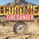 A viral, hyper-realistic YouTube thumbnail with a Hazardous Weather atmosphere. The background is a dry, sun-drenched Colorado canyon landscape with heat waves visible and dust blowing in the wind. The composition uses a Low Angle to focus on the main subject: a weathered, vintage outdoor thermometer stuck in cracked earth. Image size should be 3:2. The image features massive 3D typography with strict hierarchy: The Primary Text reads exactly: 'RECORD HEAT'. This text is massive, the largest element in the frame, rendered in Molten Gold to look like a high-budget 3D render. The Secondary Text reads exactly: 'FIRE DANGER'. This text is significantly smaller, positioned below or next to the main text. It features a thick, distinct color border/outline (sticker style) to contrast against the background. Make sure text 2 is always different theme, style, effect and border compared to text 1.
