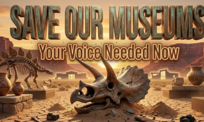 A viral, hyper-realistic YouTube thumbnail with a warm western heritage atmosphere. The background is a dramatic Colorado sunset over red rock mesas with glowing museum silhouettes in Grand Junction and Fruita. The composition uses a low-angle cinematic shot to focus on the main subject: a massive, weathered triceratops skull emerging from the sand. Image size should be 3:2. The image features massive 3D typography with strict hierarchy: The Primary Text reads exactly: 'SAVE OUR MUSEUMS'. This text is massive, the largest element in the frame, rendered in burnished bronze metal with authentic patina to look like a high-budget 3D render. The Secondary Text reads exactly: 'Your Voice Needed Now'. This text is significantly smaller, positioned below the main text. It features a thick, glowing orange outline with subtle dust particles to contrast against the background. Make sure text 2 is always different theme, style, effect and border compared to text 1.