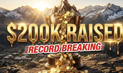 A viral, hyper-realistic YouTube thumbnail with a triumphant mountain sunrise atmosphere. The background is a majestic Colorado Rocky Mountain peak at dawn with golden sunlight breaking over snow-capped ridges and the Western Colorado University campus nestled in the valley below. The composition uses a dramatic low-angle shot to focus on the main subject: a massive, gleaming bronze mountain peak trophy overflowing with glowing golden coins and dollar bills cascading down like a waterfall. Image size should be 3:2. The image features massive 3D typography with strict hierarchy: The Primary Text reads exactly: '$200K RAISED'. This text is massive, the largest element in the frame, rendered in molten gold with realistic liquid metal drips and cinematic light flares to look like a high-budget 3D render. The Secondary Text reads exactly: 'RECORD BREAKING'. This text is significantly smaller, positioned below the main text with a bold red sticker-style outline and slight motion blur effect to contrast against the golden background. Make sure text 2 is always different theme, style, effect and border compared to text 1.