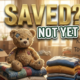 A viral, hyper-realistic YouTube thumbnail with a Heartwarming Community atmosphere. The background is a Softly lit, cluttered but organized donation center room filled with clothes and boxes matching the story with Warm, golden hour sunbeams through a window. The composition uses a Macro shot for detail to focus on the main subject: a Worn, beloved Teddy Bear sitting on a stack of folded clothes. Image size should be 3:2. The image features massive 3D typography with strict hierarchy: The Primary Text reads exactly: 'SAVED?'. This text is massive, the largest element in the frame, rendered in Gold Metal to look like a high-budget 3D render. The Secondary Text reads exactly: 'NOT YET'. This text is significantly smaller, positioned below or next to the main text. It features a thick, distinct color border/outline (sticker style) to contrast against the background. Make sure text 2 is always different theme, style, effect and border compared to text 1.