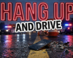 A viral, hyper-realistic YouTube thumbnail with a somber, public safety atmosphere. The background is a dimly lit American highway at dusk with flashing red and blue police lights reflecting off wet asphalt and a cracked smartphone lying face-up on the road. The composition uses a low angle to focus on the main subject: a shattered cell phone on the highway center line with glass fragments scattered around it, no human faces visible. Image size should be 3:2. The image features massive 3D typography with strict hierarchy: The Primary Text reads exactly: 'HANG UP'. This text is massive, the largest element in the frame, rendered in glowing crimson neon tubing to look like a high-budget 3D render. The Secondary Text reads exactly: 'AND DRIVE'. This text is significantly smaller, positioned below the main text. It features a thick white border outline in sticker style to contrast against the dark highway background. Make sure text 2 is always different theme, style, effect and border compared to text 1. The text materials correspond to the story's concept. Crucial Instruction: There is absolutely NO other text, numbers, watermarks, or subtitles in this image other than these two specific lines. 8k, Unreal Engine 5, cinematic render.