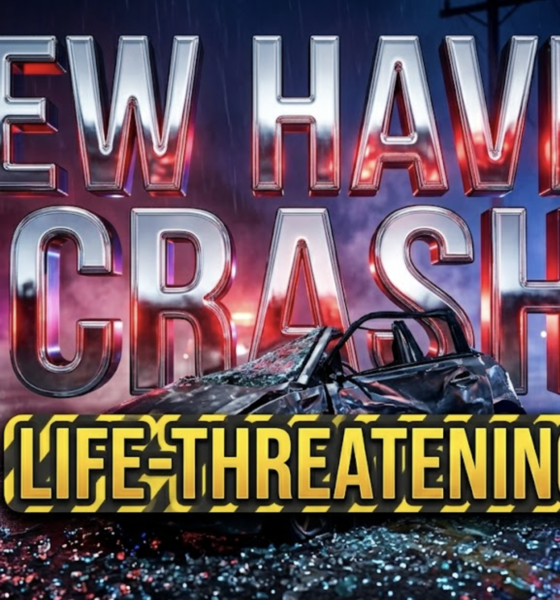 A viral, hyper-realistic YouTube thumbnail with a dramatic nighttime emergency atmosphere. The background is a dark rural intersection with flashing red and blue emergency lights casting dramatic shadows across wet pavement, with a utility pole visible in the distance and emergency vehicles creating a tense scene. The composition uses a low angle Dutch tilt to emphasize the severity and chaos of the accident scene. The main subject is a crumpled car door with shattered glass fragments catching the emergency lights, positioned prominently in the foreground with rescue equipment nearby. Image size should be 3:2. The image features massive 3D typography with strict hierarchy: The Primary Text reads exactly: 'NEW HAVEN CRASH'. This text is massive, the largest element in the frame, rendered in metallic chrome with emergency light reflections and urgent red glow effects to look like a high-budget 3D render. The Secondary Text reads exactly: 'LIFE-THREATENING'. This text is significantly smaller, positioned below the main text. It features a thick, distinct yellow and black caution-stripe border outline (sticker style) to contrast against the background. Make sure text 2 is always different theme, style, effect and border compared to text 1. The text materials correspond to the story's concept. Crucial Instruction: There is absolutely NO other text, numbers, watermarks, or subtitles in this image other than these two specific lines. 8k, Unreal Engine 5, cinematic render