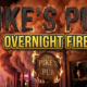 A viral, hyper-realistic YouTube thumbnail with a dramatic emergency atmosphere. The background is a nighttime commercial building exterior with billowing smoke clouds illuminated by red and orange emergency lights, creating an intense amber glow against the dark sky. The composition uses a low angle shot to focus on the main subject: a weathered wooden pub sign with flames licking at its edges, emergency vehicle lights reflecting off broken windows in the background. Image size should be 3:2. The image features massive 3D typography with strict hierarchy: The Primary Text reads exactly: 'PIKE'S PUB'. This text is massive, the largest element in the frame, rendered in charred wood texture with glowing ember edges to look like a high-budget 3D render. The Secondary Text reads exactly: 'OVERNIGHT FIRE'. This text is significantly smaller, positioned below the main text. It features a thick, distinct yellow and black border outline in bold sans-serif style to contrast against the smoky background. Make sure text 2 is always different theme, style, effect and border compared to text 1. The text materials correspond to the story's concept. Crucial Instruction: There is absolutely NO other text, numbers, watermarks, or subtitles in this image other than these two specific lines. 8k, Unreal Engine 5, cinematic render.