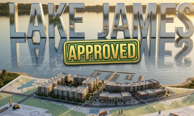 A viral, hyper-realistic YouTube thumbnail with a lakeside development atmosphere. The background is a serene lakefront scene with modern architectural blueprints overlaying a natural Indiana lake setting, featuring golden hour lighting reflecting off calm water. The composition uses a wide-angle aerial view to focus on the main subject: a detailed 3D architectural model of mixed-use buildings positioned on a topographic map of Lake James shoreline, with miniature construction elements and planning documents visible. Image size should be 3:2. The image features massive 3D typography with strict hierarchy: The Primary Text reads exactly: 'LAKE JAMES'. This text is massive, the largest element in the frame, rendered in polished chrome with water reflection effects to look like a high-budget 3D render. The Secondary Text reads exactly: 'APPROVED'. This text is significantly smaller, positioned below the main text. It features a thick, distinct green and gold border/outline (sticker style) with a stamped approval seal effect to contrast against the background. Make sure text 2 is always different theme, style, effect and border compared to text 1. The text materials correspond to the story's concept. Crucial Instruction: There is absolutely NO other text, numbers, watermarks, or subtitles in this image other than these two specific lines. 8k, Unreal Engine 5, cinematic render