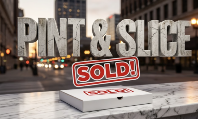 A viral, hyper-realistic YouTube thumbnail with a sophisticated business atmosphere. The background is a blurred, bustling city street at dusk in Fort Wayne, with bokeh lights and a subtle glow. The composition uses a low angle shot to focus on the main subject: a single, pristine white pizza box with a "SOLD" sign sticker on it, resting on a polished marble countertop. Image size should be 3:2. The image features massive 3D typography with strict hierarchy: The Primary Text reads exactly: 'PINT & SLICE'. This text is massive, the largest element in the frame, rendered in distressed, cracked concrete to look like a historic monument. The Secondary Text reads exactly: 'SOLD!'. This text is significantly smaller, positioned below the main text. It features a thick, vibrant red border/outline (sticker style) to contrast against the background.