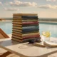JPMorgan 2026 summer reading list books stacked on a poolside private-bank table.